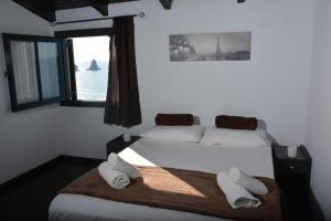 a bedroom with a bed with two pillows and a window at Sandy Coast Hospitality in Agios Gordios