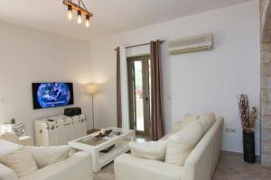 a living room with two white couches and a tv at Selinitsa Stone Home - Mani's Private Pool Retreat in Agios Nikolaos