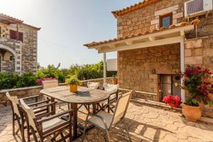a patio with a table and chairs and a fireplace at Mani's Aura Seaside-Enchanting Stone Gem in Kotrónion