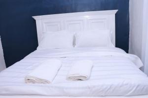 ein weißes Bett mit weißen Kissen und Handtüchern darauf in der Unterkunft Lulu Stays 1 Bedroom in Nyahururu