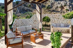 a patio with two couches and a stone wall at Atlantic Cave Haven-Seaside, Fully Equipped in Kolymbia