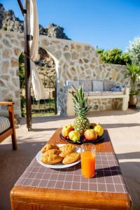 a plate of fruit and bread on a table with a glass of orange juice at Atlantic Cave Haven-Seaside, Fully Equipped in Kolymbia