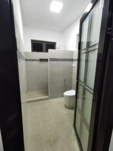 a bathroom with a toilet and a glass door at Cosy apartment on the 1st floor in Curepipe