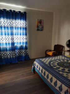 a bedroom with a bed and a blue curtain at Cosy apartment on the 1st floor in Curepipe