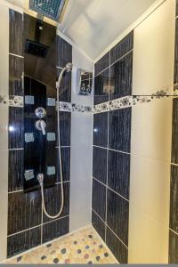 baño con ducha de azulejos negros en Chambres d'Hôtes La Vigneronne, en Senouillac