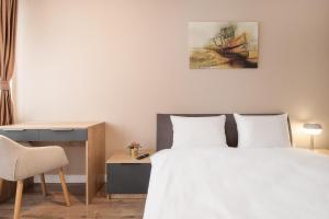 a bedroom with a white bed and a desk and a bed at Maniu Flats in Oradea