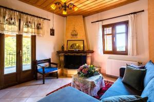 een woonkamer met een blauwe bank en een open haard bij Stemnitsa Stone Residence - Comfy Mountain Getaway in Stemnitsa