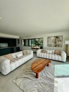 una sala de estar con 2 sofás blancos y una mesa de madera. en Villa neuve vue sur la mer n°1, en Olmeto