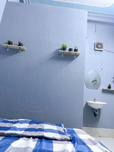 1 dormitorio con pared azul, cama y lavamanos en Nhà Nghỉ Thành Đạt, en Can Tho