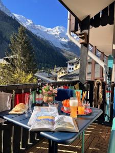 a table on a balcony with a book and drinks at Le Petit Cham in Chamonix-Mont-Blanc