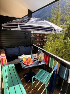 a table and chairs on a balcony with an umbrella at Le Petit Cham in Chamonix