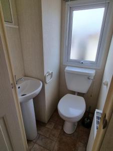 a bathroom with a toilet and a sink and a window at OneDoor Apartman in Szuha