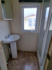 baño con lavabo, ventana y ducha en OneDoor Apartman, en Szuha