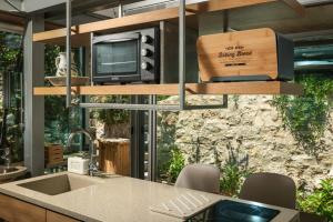 uma cozinha com um lavatório, um micro-ondas e uma televisão em Luxury TreeHouse - A breath away from the beach em Loutrákion