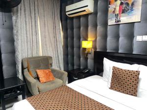 Habitación de hotel con cama y silla en Newland Luxury Hotels and Apartments, en Abuja