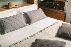 uma cama com almofadas cinzentas e brancas em Luxury TreeHouse - A breath away from the beach em Loutrákion