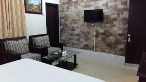 Habitación con 2 sillas, mesa y TV. en Hotel Rise Inn en Karachi