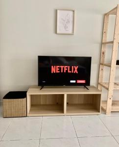 una TV a schermo piatto seduta sopra un centro di intrattenimento in legno di Caparica Coast Townhouse Apartments a Charneca