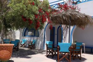 un grupo de mesas y sillas bajo una sombrilla de paja en Santorini Seaside Retreat - Flora's Summer Escape en Perissa