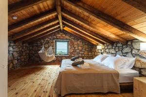 ein Schlafzimmer mit einem Bett und einer Steinmauer in der Unterkunft Gerakada Exclusive-Seaview Villa with Private Pool in Koroni