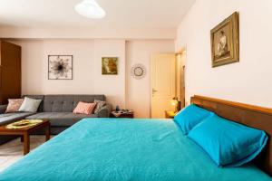 a bedroom with a blue bed and a couch at Kalamata City Nest - Central & Cozy Hideout in Kalamata