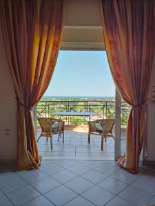 Habitación con cortinas y balcón con mesa y sillas. en Schinias Bright Spacious Maisonette-Panoramic View, en Maratón