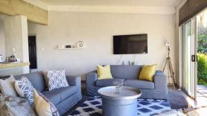 sala de estar con sofá azul y TV en Under Milkwood en Chintsa
