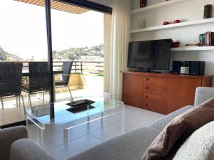 a living room with a glass coffee table and a television at Girbal Terrace in Tossa de Mar