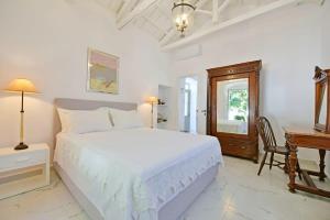 a white bedroom with a large bed and a desk at A Sea-licious Vacation - Chic & Style in Hydra in Hydra