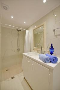 a white bathroom with a sink and a shower at A Sea-licious Vacation - Chic & Style in Hydra in Hydra