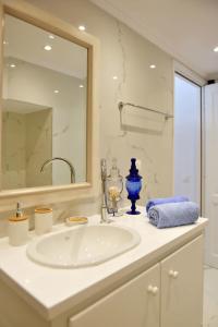 La salle de bains blanche est pourvue d'un lavabo et d'un miroir. dans l'établissement A Sea-licious Vacation - Chic & Style in Hydra, à Hydra