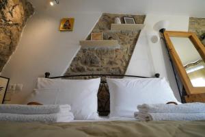 1 cama con almohadas blancas y espejo en una habitación en Vilaeti Stone House - Cretan Cozy Nest, en Agios Konstantinos