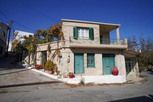 a small house with green doors and a balcony at Vilaeti Stone House - Cretan Cozy Nest in Agios Konstantinos