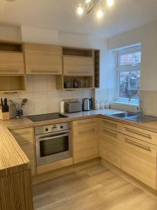 Park Cottage - Cosy 1 bedroom في Spinney Hill: مطبخ بدولاب خشبي وفرن علوي موقد