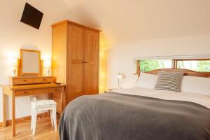 a bedroom with a bed and a desk with a mirror at Dartmoor Barn on North Hessary Tor in Yelverton