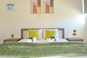 ein Schlafzimmer mit einem Bett mit grüner Bettwäsche und gelben Kissen in der Unterkunft SeaWitch Apartment in Larnaka