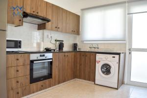 eine Küche mit Holzschränken und einer Waschmaschine in der Unterkunft SeaWitch Apartment in Larnaka