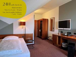 a hotel room with a bed and a desk with a television at Classik Hotel Magdeburg in Magdeburg