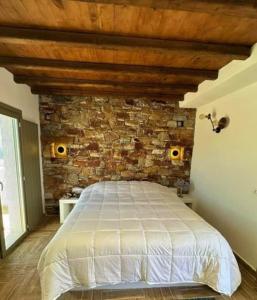 Un dormitorio con una pared de ladrillo y una cama en Ligaria Stone Maisonette Gem in Folegandros Heart, en Áno Meriá