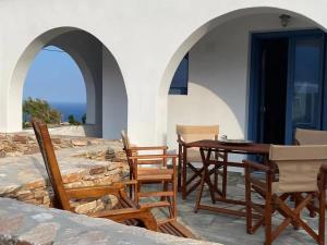 un patio con sillas y una mesa de madera. en Folegandros Enchanting Cycladic Home Sunset Views en Áno Meriá