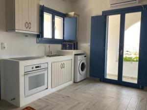 cocina con armarios azules, lavadora y secadora en Folegandros Enchanting Cycladic Home Sunset Views en Áno Meriá