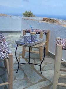 Áno Meriá的住宿－Folegandros Enchanting Cycladic Home Sunset Views，天井上的桌子,带两杯和两把椅子