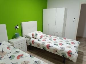 1 dormitorio con 2 camas y pared verde en Apartamento confort I, en La Seu d'Urgell