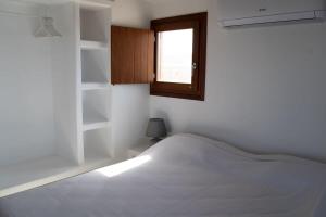 una camera bianca con un letto e una finestra di Folegandros Serenity - Livadaki Summer Hideaway ad Áno Meriá