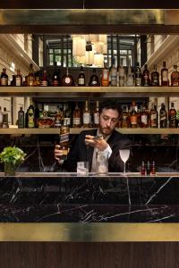 Um homem atrás de um bar a olhar para o telemóvel. em Hotel Casa Lucia em Buenos Aires