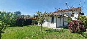 a small white house in a yard with trees at La Casa di Rina in Angera