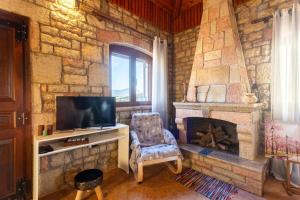 a stone walled living room with a tv and a fireplace at Polilimnio Mini Castle - Fotini's Unique Eco Gem in Aristoménis
