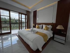 a bedroom with a large bed and large windows at Royal Maharani Payogan in Ubud