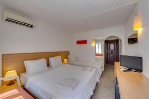 a bedroom with a white bed and a flat screen tv at Serhan Hotel in Gümbet