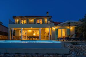 a villa with a swimming pool at night at Villa BEACHFRONT in Klimno
